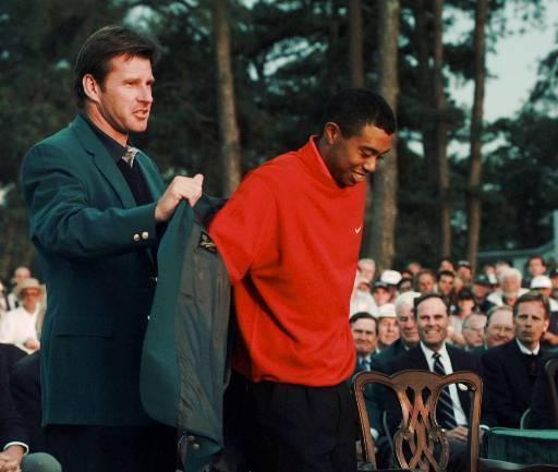 Previous winner Nick Faldo helps Woods on with the jacket in 1997