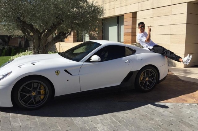 Ronaldo poses on the boot of one of his white Ferraris