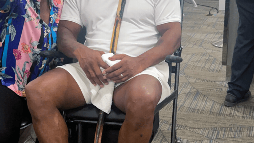 , Mike Tyson, 56, pictured in wheelchair holding walking stick as fearsome boxing legend is pushed through Miami airport