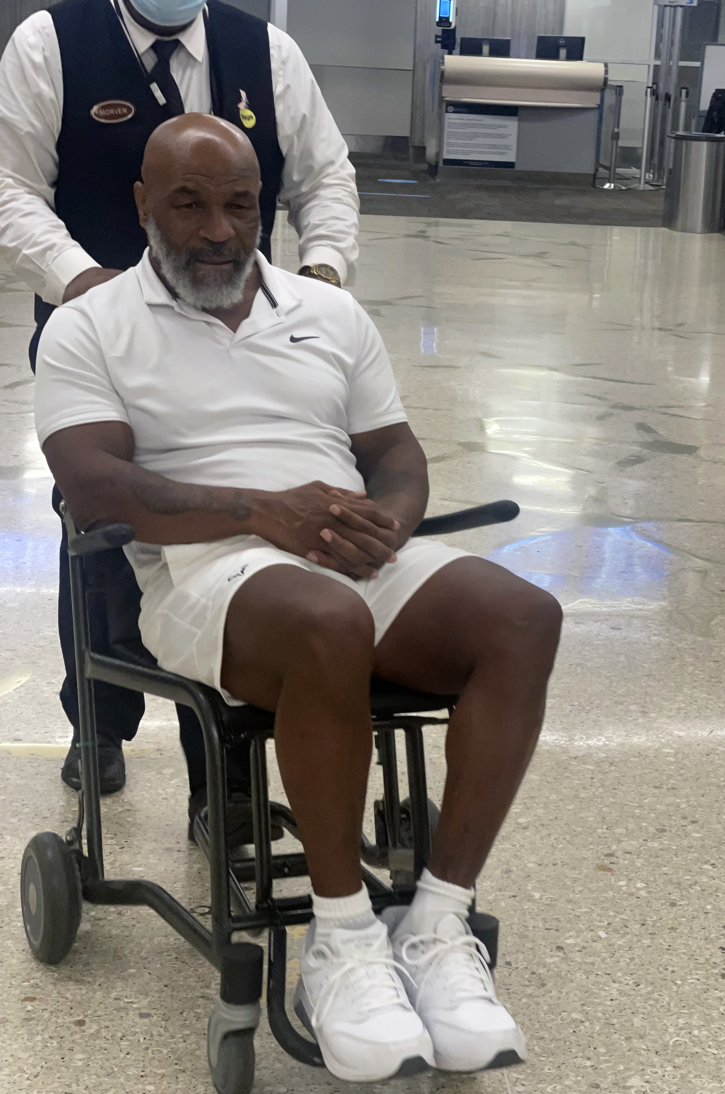 , Mike Tyson, 56, pictured in wheelchair holding walking stick as fearsome boxing legend is pushed through Miami airport