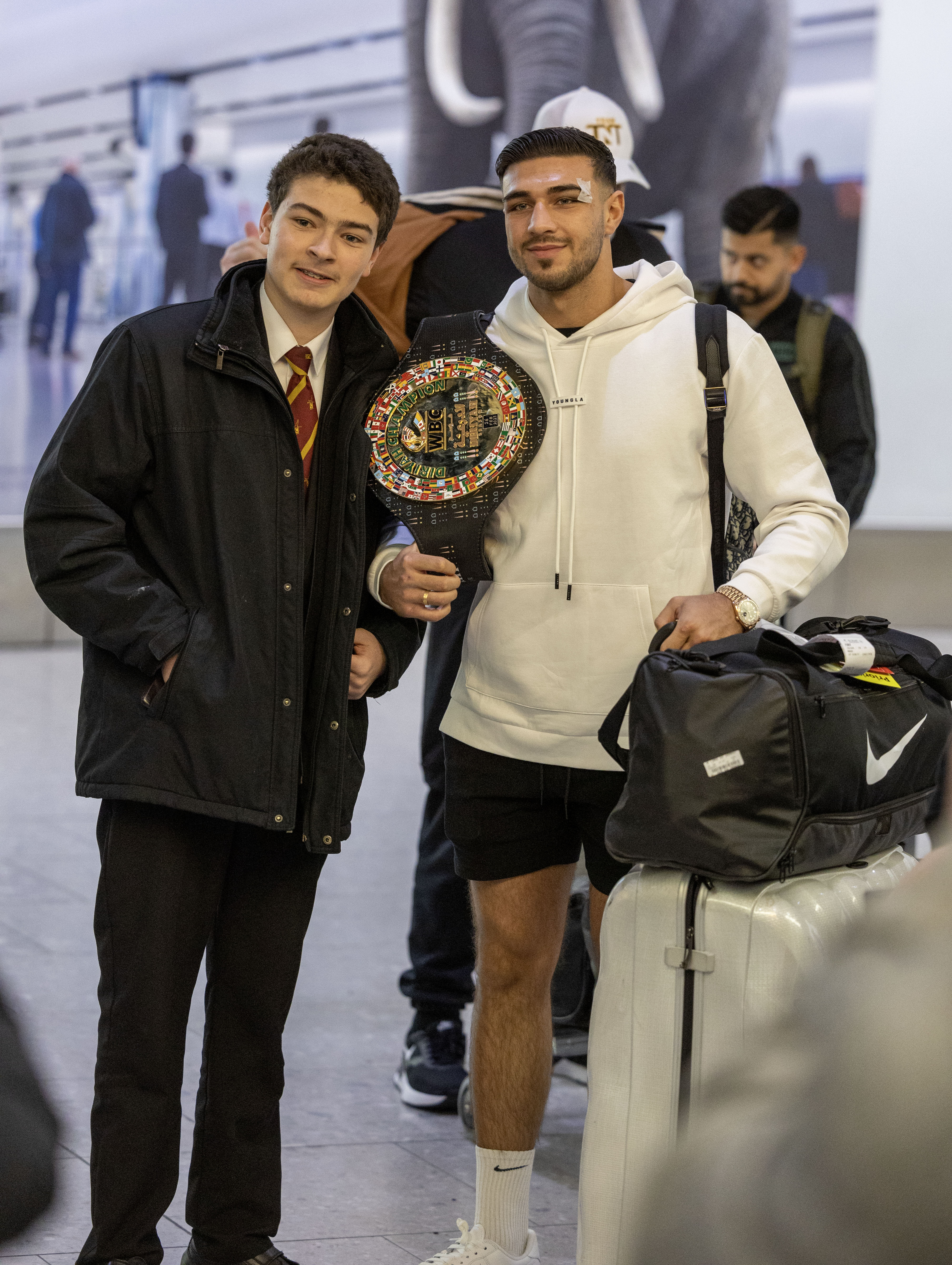 , Bruised Tommy Fury beams as he touches down at Heathrow with brother Tyson and dad John after huge win over Jake Paul